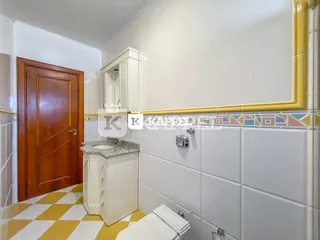 Foto de um ambiente interno com piso xadrez amarelo e branco e um armário branco.