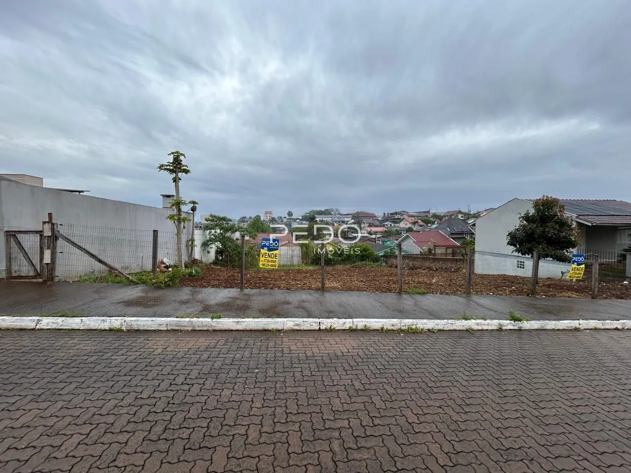 Vista da propriedade com cerca e terreno no fundo.