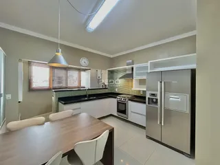 Foto de uma cozinha e sala de jantar com armários brancos.