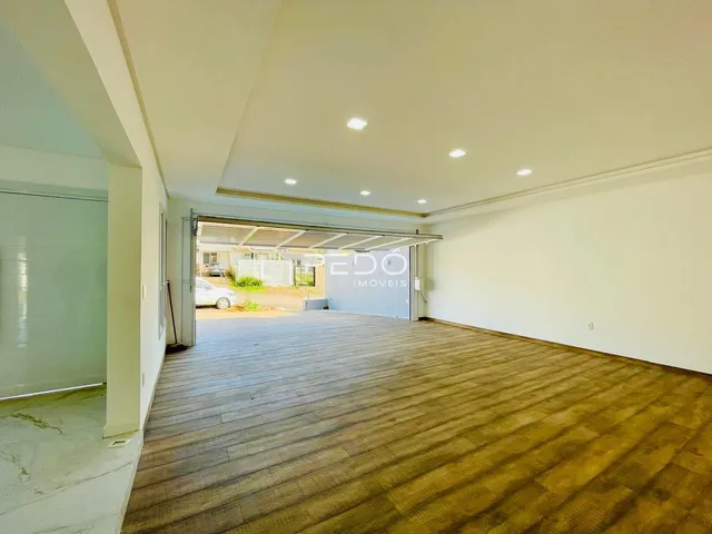 Interior de uma sala ampla com piso de madeira e acesso a uma área externa.