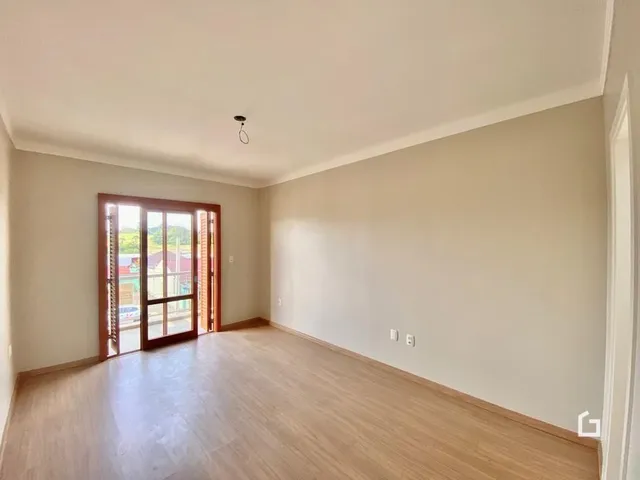 Vista interna de uma sala com piso de madeira e porta de vidro.