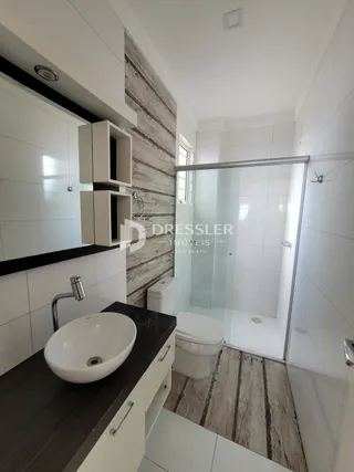 Banheiro moderno com revestimento de cerâmica e box de vidro.
