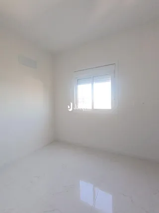 Ambiente interno de uma sala com paredes brancas e piso claro.