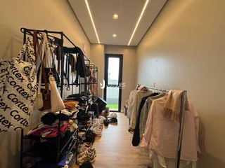 Hall de corredor interno com roupas penduradas e portas de saída.