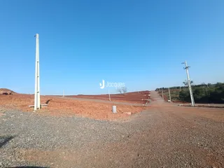 Paisagem de terra vermelha com estruturas de concreto no horizonte.