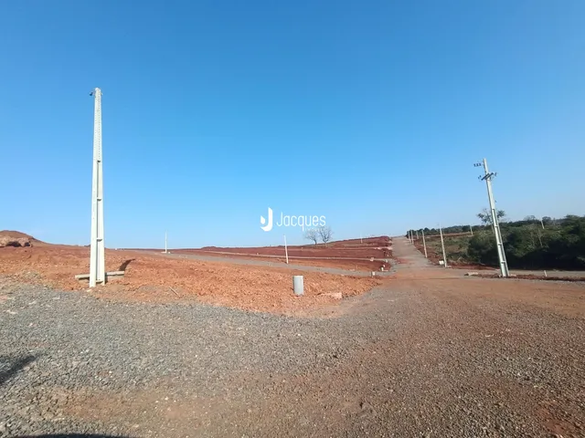 Paisagem de terra vermelha com estruturas de concreto no horizonte.