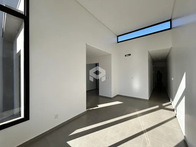 Vista de um corredor interno com paredes brancas e piso de cerâmica.