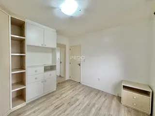 Ambiente interno com armários brancos e piso de madeira clara.