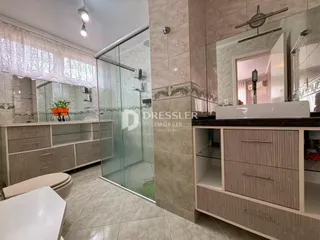Interior de um banheiro com box de vidro e armários em Lajeado.