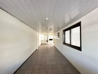 Foto de um corredor interno com piso de cerâmica e paredes brancas.