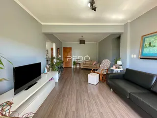 Sala de estar ampla com piso de madeira e sofá cinza.