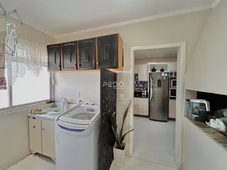 Vista de uma cozinha com armários e máquina de lavar roupa em um imóvel no Brasil.