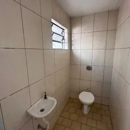 Foto de um banheiro com paredes brancas e piso de cerâmica.
