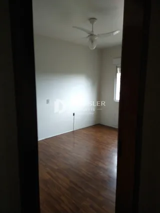 A sala apresenta piso de madeira e paredes brancas.