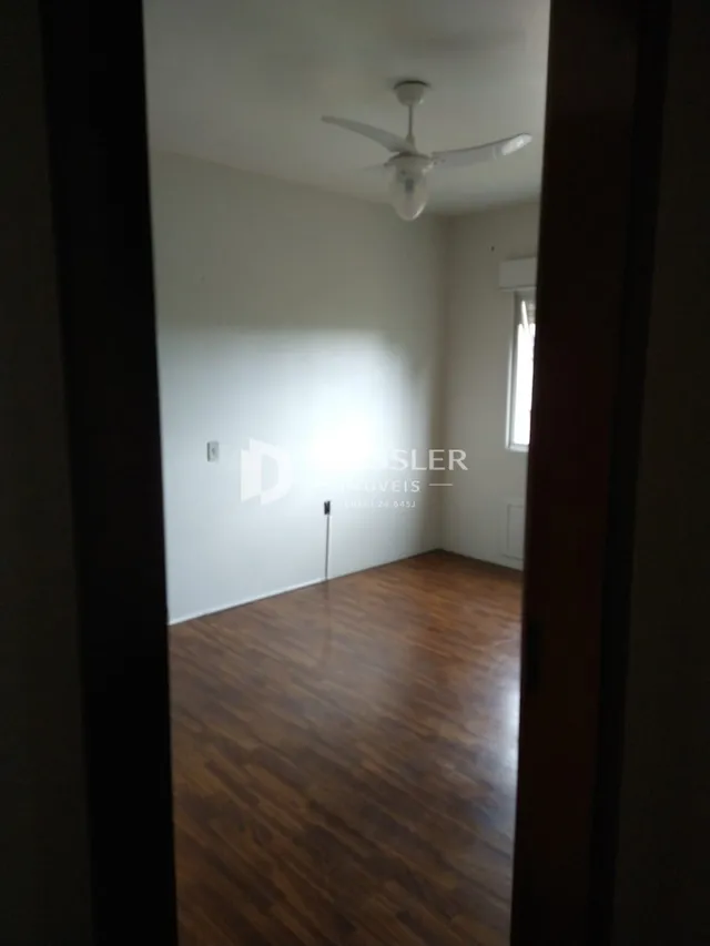 A sala apresenta piso de madeira e paredes brancas.