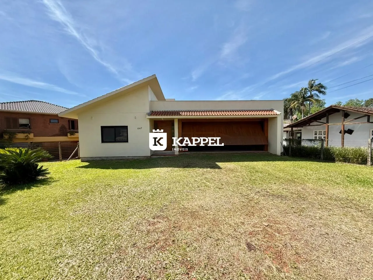 Fachada de uma casa em Lajeado, Brasil, com jardim gramado e garagem coberta.