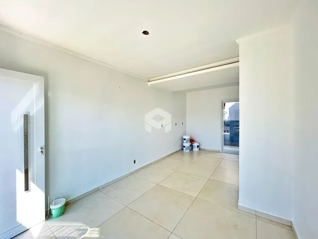 Ambiente interno de uma sala ampla com paredes brancas e piso de cerâmica.