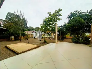 Área externa pavimentada com piso de cerâmica e estrutura de madeira.