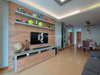 A sala de estar apresenta painéis de madeira e uma televisão montada na parede.