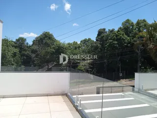 Vista da área externa com muro branco e grade de vidro.