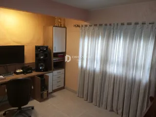 Sala de estar com televisão e cortinas claras.