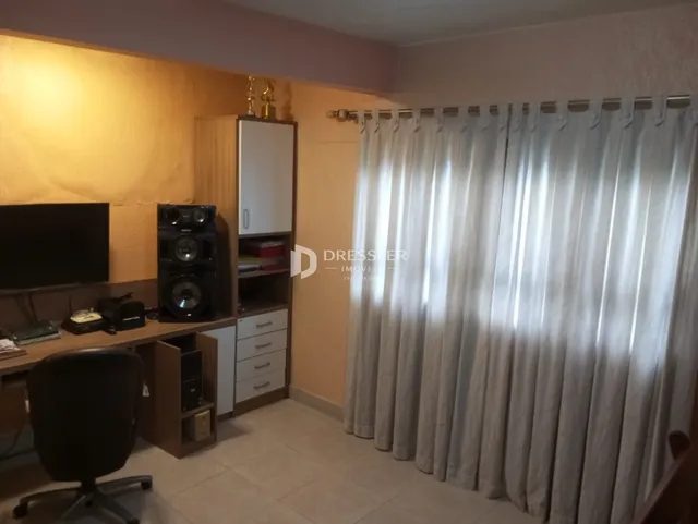 Sala de estar com televisão e cortinas claras.