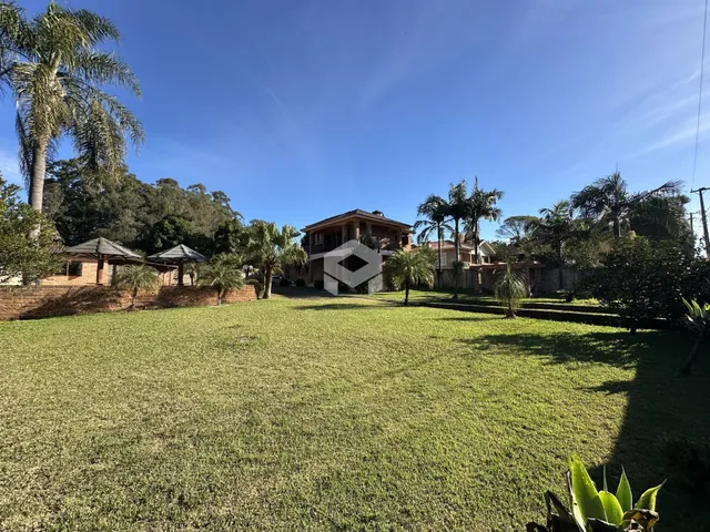 Vista externa de uma propriedade com gramado verde e vegetação.