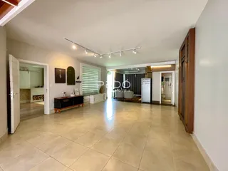 Sala de estar ampla com piso de cerâmica clara e portas de acesso a outras áreas.