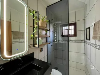 Foto de um banheiro com revestimento de cerâmica e box de vidro.