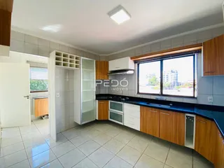 Uma cozinha com armários de madeira e piso cerâmico em um imóvel no Brasil.