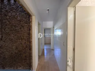 Corredor interno de uma residência com parede de pedra exposta.