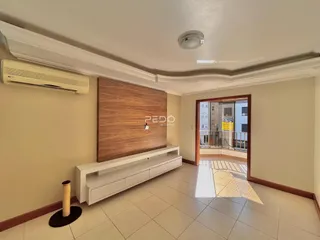 Sala de estar com parede de destaque em madeira e piso de cerâmica clara.