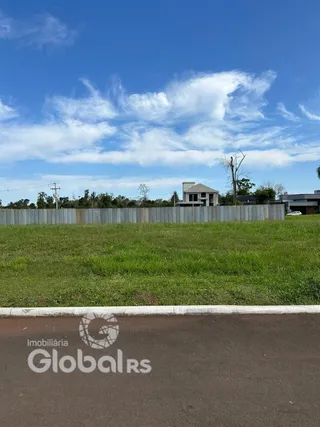 Vista externa de uma propriedade com gramado e cerca no fundo.
