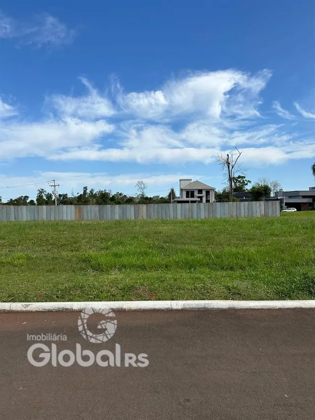 Vista externa de uma propriedade com gramado e cerca no fundo.