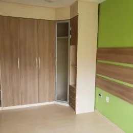 Quarto com painéis de madeira clara e porta interna.