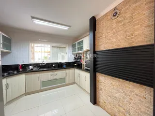 Interior de uma cozinha com piso de cerâmica e armários brancos.
