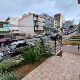 Varanda externa com piso de cerâmica e vegetação no ambiente residencial.