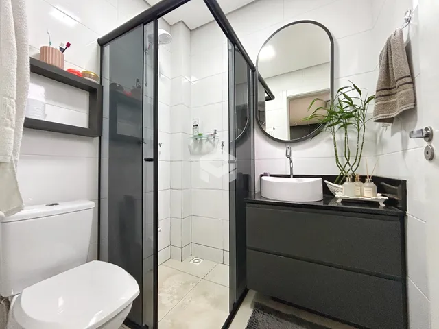 Interior de um banheiro moderno com box de vidro e revestimento branco.