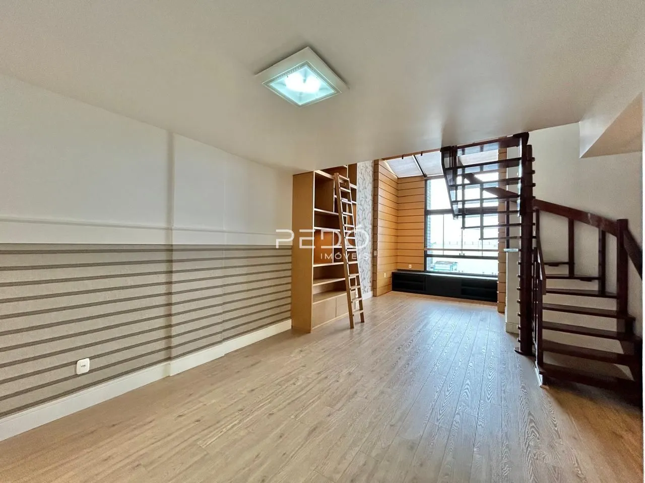 Sala de estar com piso de madeira e escadaria de madeira.