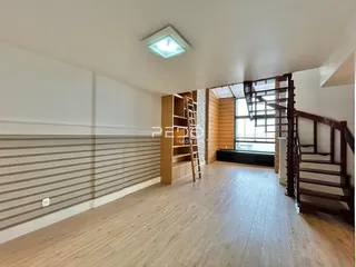 Sala de estar com piso de madeira e escadaria de madeira.