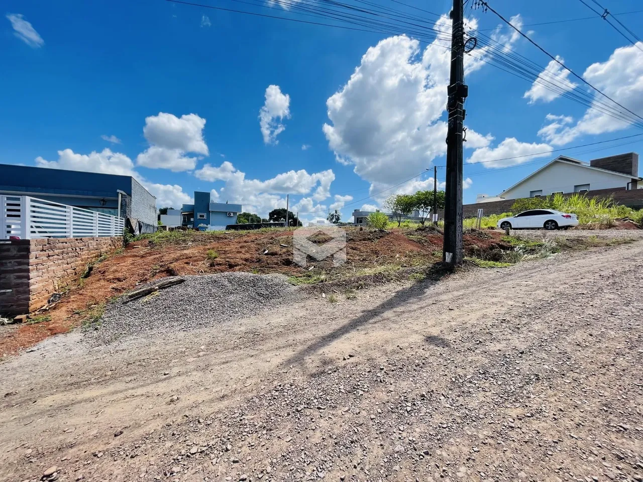 Vista externa de uma propriedade com terreno e estrada de terra.