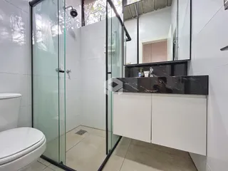 Banheiro moderno com box de vidro e louças brancas.