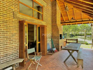 Vista da fachada de uma casa com parede de tijolos e área externa de pátio.