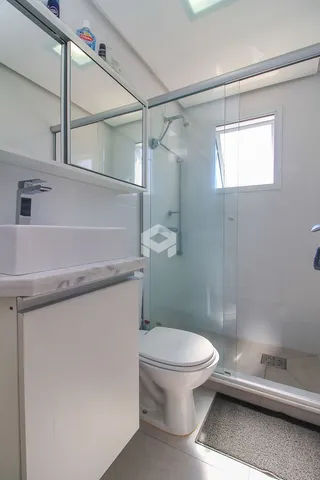Foto interna de um banheiro com box de vidro e vaso sanitário branco.