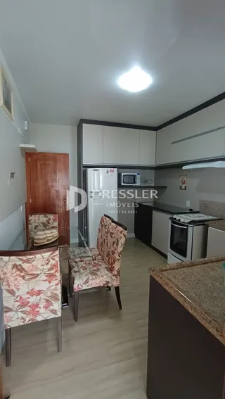 Ambiente interno de uma sala com móveis e cozinha visíveis.
