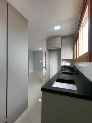 Vista da cozinha moderna com armários e bancada escura.
