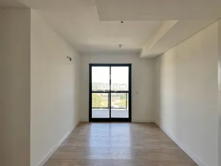 Interior de um ambiente com piso de madeira e grande janela.