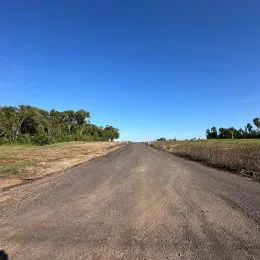 Vista de uma estrada de terra em uma paisagem aberta sob um céu azul claro.