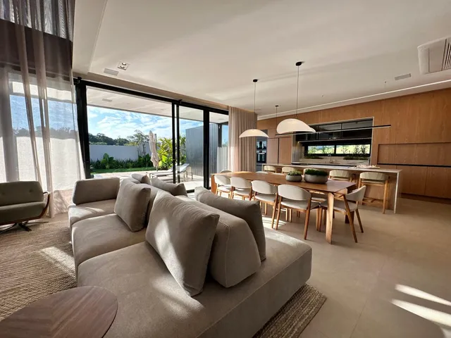 Sala de estar com sofá grande e portas de vidro que dão vista para o exterior.
