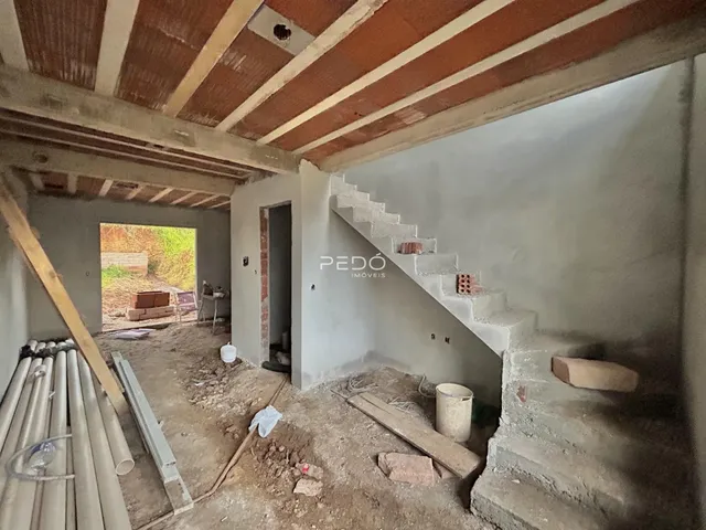 Foto de um ambiente interno em construção com estrutura de teto exposta.